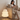 Woman sitting on a couch using a phone next to a modern lamp in a cozy living room.