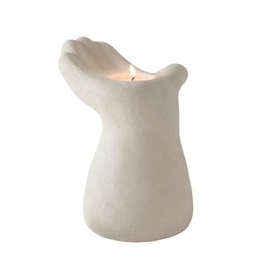 Modern white sculptural candle holder shaped like a hand holding a lit candle, minimalist home décor