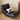 Black leather chair with a white pillow featuring a black horse design on a wooden floor.