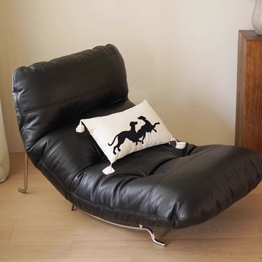 Black leather chair with a white pillow featuring a black horse design on a wooden floor.