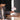 Person interacting with a small white lamp on a wooden table