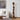 A tall, sculptural wooden floor sculpture with stacked organic shapes stands in a modern living room next to a white sofa and abstract wall art.