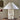 Table lamp with textured white shade on a wooden stump against a beige wall.