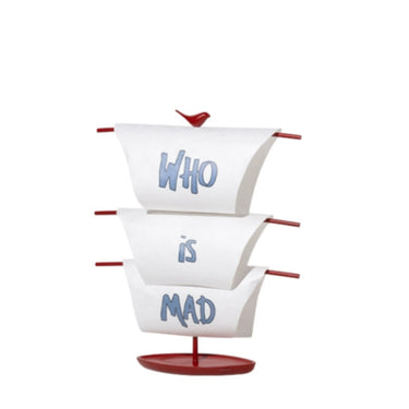 A decorative table lamp with white lampshade with the words 'WHO' and 'IS MAD' printed on it, and a red base and switch.