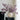 Vase with purple flowers on a black surface against a white wall