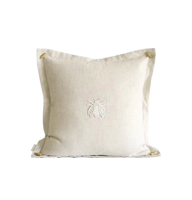 Beige pillow with a bee emblem on a white background