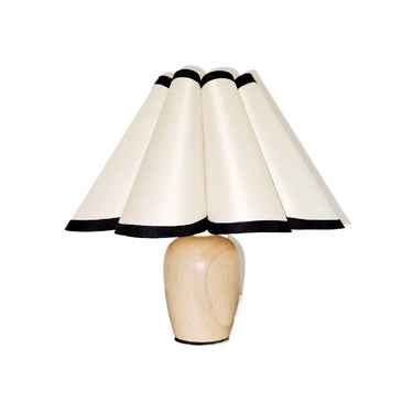 Modern table lamp with natural wood base and wide cream lampshade edged in black for home décor