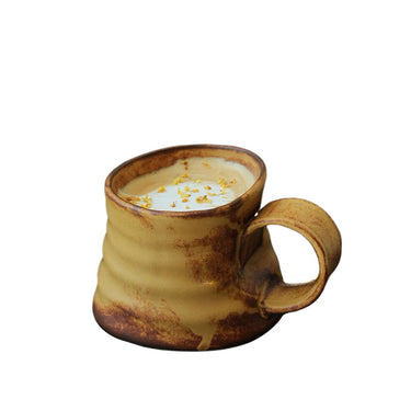 A beige and brown ceramic mug with a handle, filled with a liquid, against a white background.