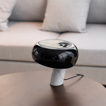 Black and white electronic device on a table with a sofa in the background