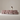 Large pink sofa with a person standing behind it against a plain wall.