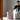 Woman reading a book next to a textured pink side table with a glass on it.