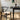 Black chair with woven seat next to a black dining table in a room with framed artwork on the wall.
