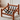 A wooden armchair with a warm medium-brown finish and black webbing straps, shown in a bright room on a textured rug.