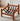 A wooden armchair with a warm medium-brown finish and black webbing straps, shown in a bright room on a textured rug.