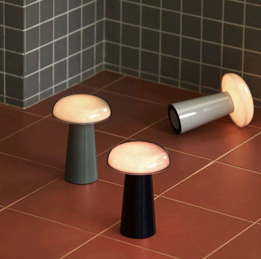 Three modern stools with different colored bases on a tiled floor.